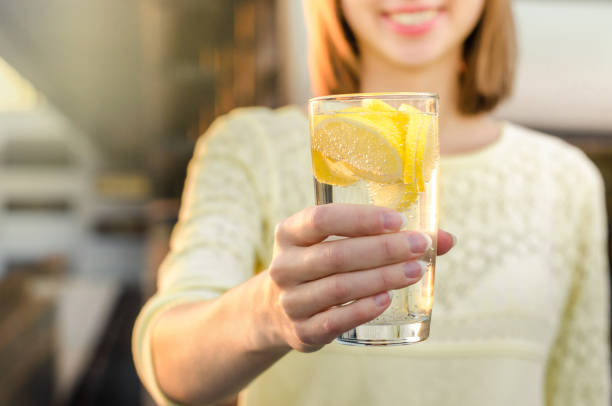 régime alimentaire. une alimentation saine. main de femme tenant le verre de limonade sur le fond flou nature en plein air. jus de légumes frais de cure de désintoxication. mode de vie sain, nourriture végétarienne. concept de nutrition. - waterlemon photos et images de collection