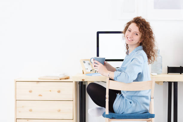 istock Positive cheerful young Caucasian female programmer or startupper looking and smiling at the camera during small break,downloads program at laptop computer 962531766