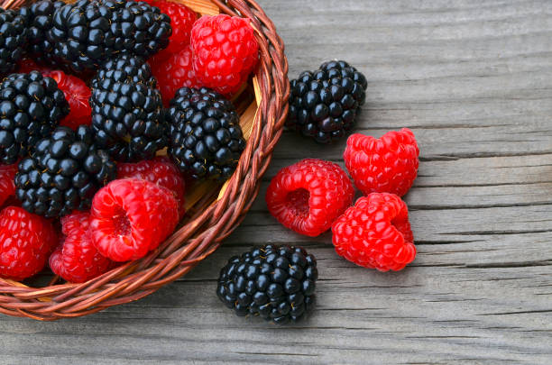 Freshly picked organic blackberries and raspberries in a basket on old wooden table.Healthy eating,vegan food or diet concept. stock photo