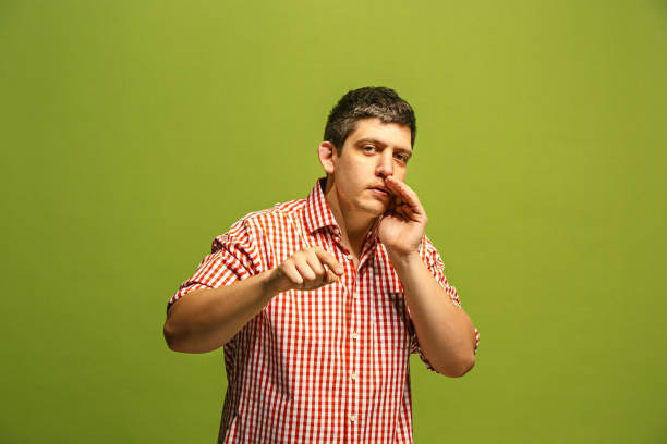 istock The young man whispering a secret behind her hand over green background 962543328