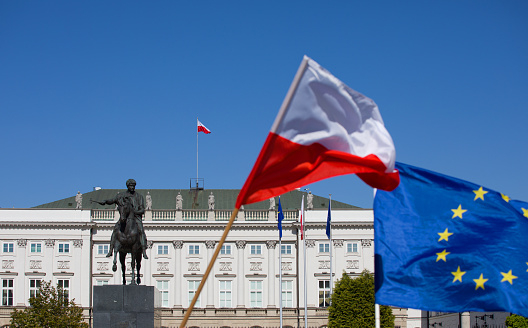 Flag of Poland and the European Union flag against the background of the Presidential Palace in Warsaw.