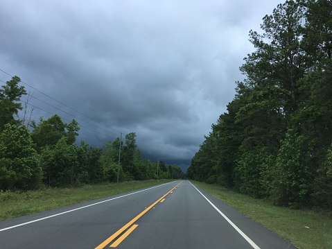 View from the driver's seat, looking down a  country road with dark, menacing clouds ahead. Photo taken in Wakulla county, Florida on iPhone 6s