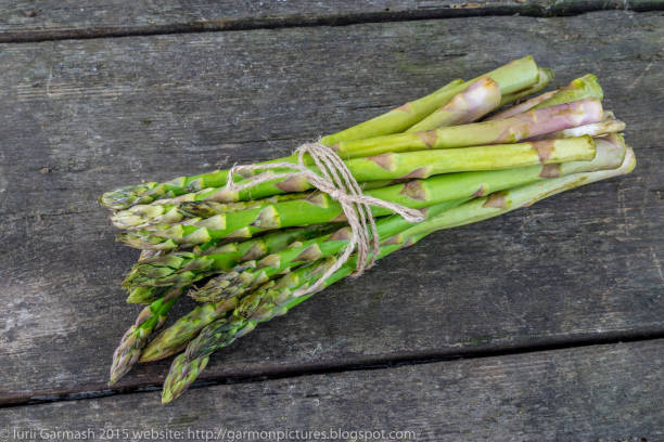 istock Asparagus bunch on a rustic wooden background. 962558782