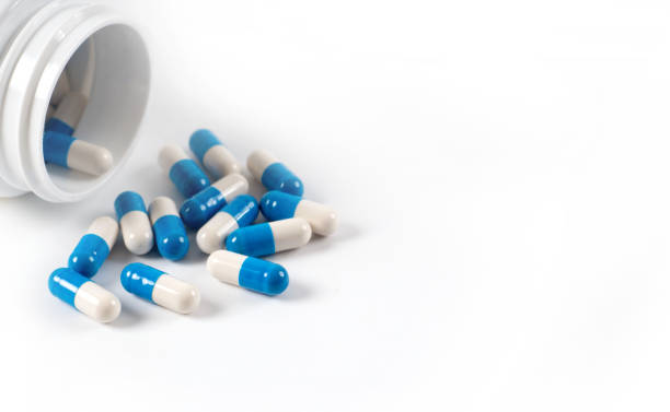 istock Drug capsule pills with blue  medication in pile, isolated 962560232