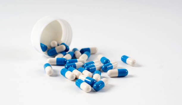 istock Drug capsule pills with blue  medication in pile, isolated 962560348
