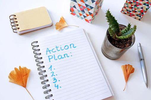 action plan written in notebook on white table