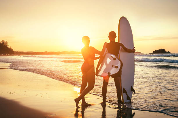 istock Couple surfers stay on sunset ocean beach 962567700