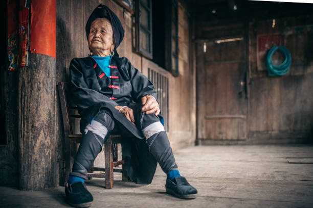istock old minority chinese woman sitting on stool indoors 962568836