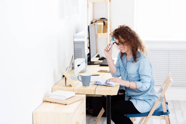 istock Young creative designer has difficulty in preparing for a project in production, trying to write good ideas into a working notebook.Indoor shot of serious concentrated business lady 962569064