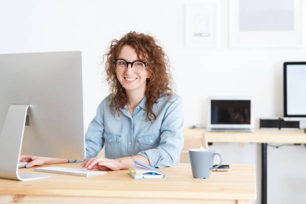 istock Attractive female freelancer works remotely at home uses wireless internet connection,sits at work place,surrounded by computers and gadgets 962570278