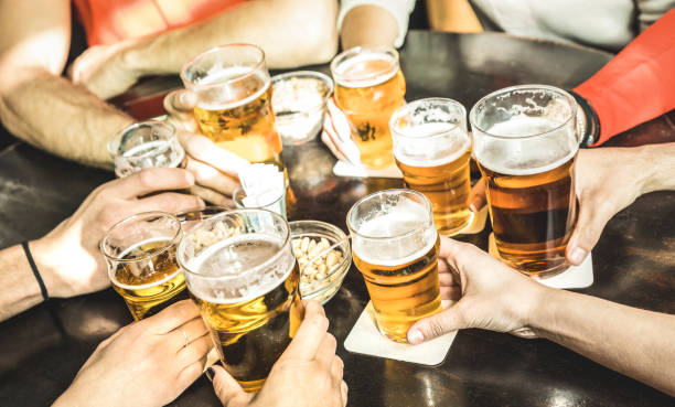 friends hands drinking beer at brewery pub restaurant - friendship concept with young people enjoying time together and having genuine fun at cool vintage brew bar - focus on middle right small glass - irish culture beer drinking pub imagens e fotografias de stock