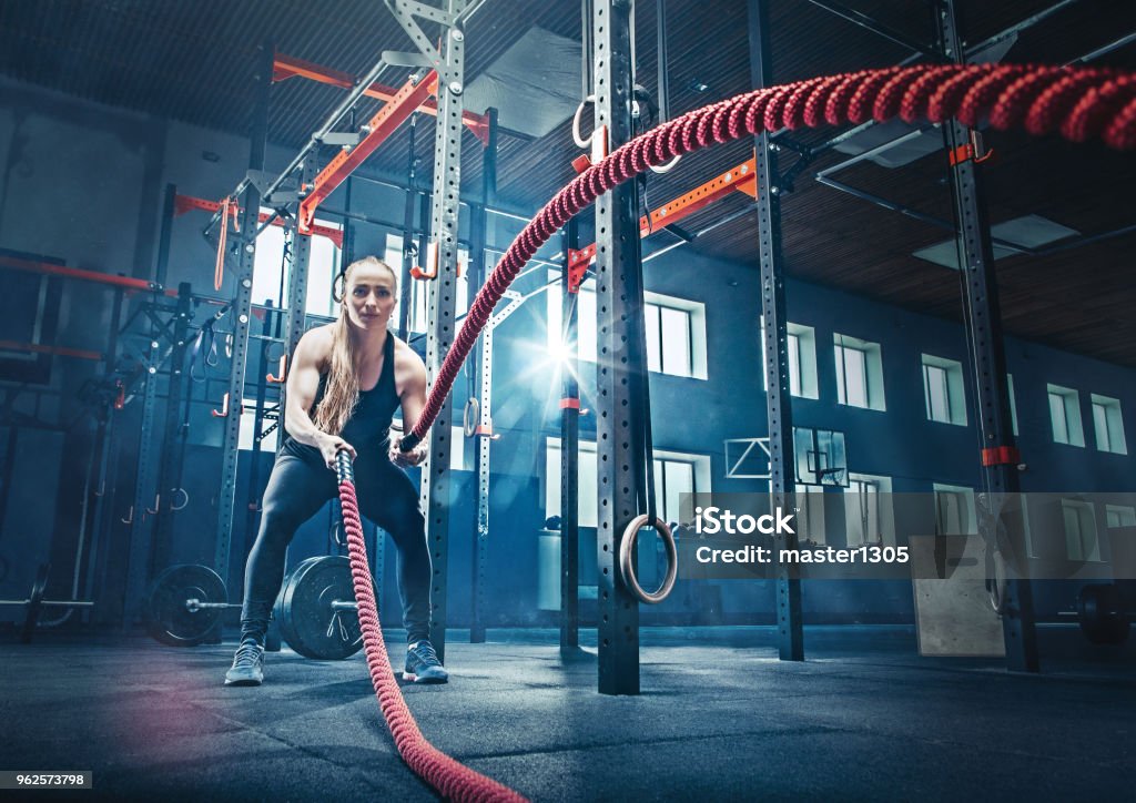 Woman with battle rope battle ropes exercise in the fitness gym Woman with battle rope battle ropes exercise in the fitness gym.. gym, sport, rope, training, athlete, workout, exercises concept Gym Stock Photo