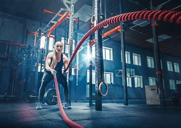 женщина с боевой веревкой боевой веревки упражнения в фитнес-зале - gym health club school gymnasium exercising стоковые фото и изображения