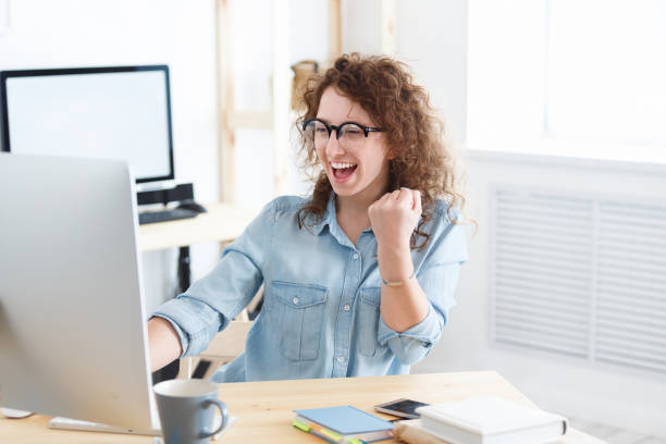 istock Beautiful young optimistic female model has broad happy smile reads necessary information in laptop from her boss. Successful advancement on a career ladder 962577100