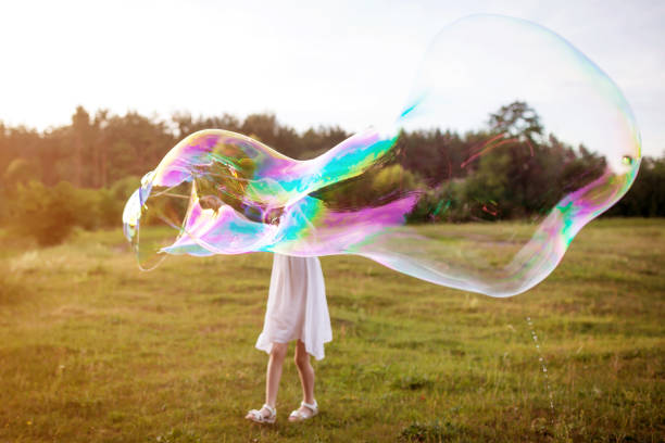 istock Little girl making a big soap bubble. Focus on the soap bubble. Summer meadow. 962579014