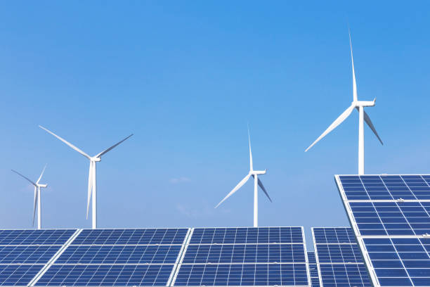 istock Rows array of  polycrystalline silicon solar panels and wind turbines generating electricity in hybrid power plant systems station 962579622