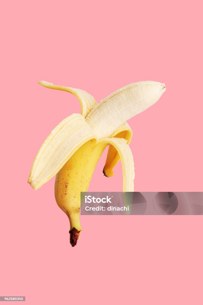 Half peeled banana on a pink background. Banana Stock Photo