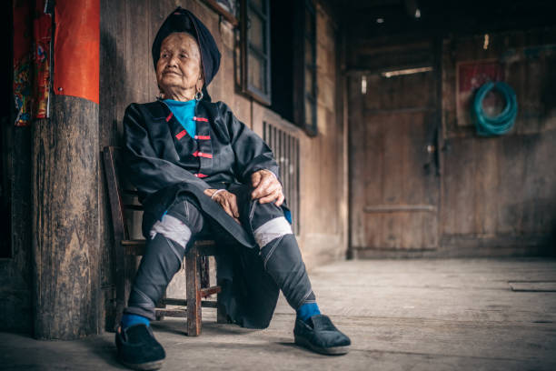istock old minority chinese woman sitting on stool indoors 962580828