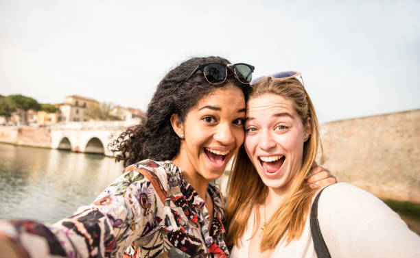 Happy multiracial girlfriends taking selfie and having fun outddors - Friendship concept with girls at spring break travel - Modern lifestyle with female best friends women - Bright day filter tone Happy multiracial girlfriends taking selfie and having fun outddors - Friendship concept with girls at spring break travel - Modern lifestyle with female best friends women - Bright day filter tone gay person photos stock pictures, royalty-free photos & images