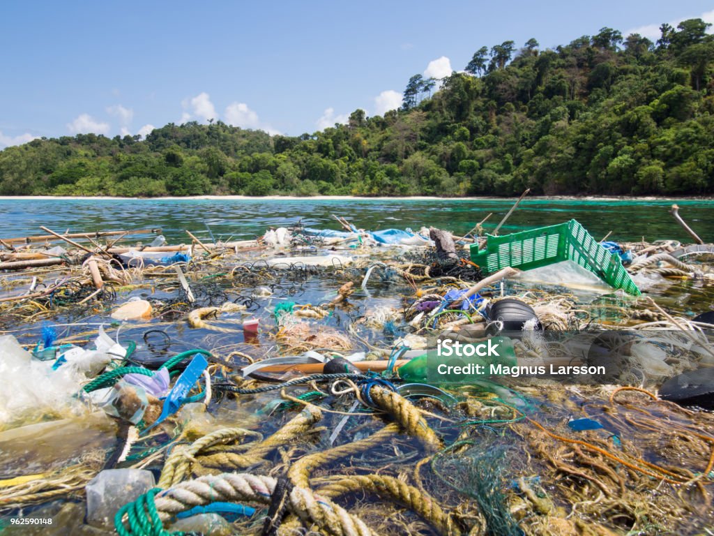 Ocean debris Big patch of ropes and garbage floating on the surface in front of a tropical island Sea Stock Photo