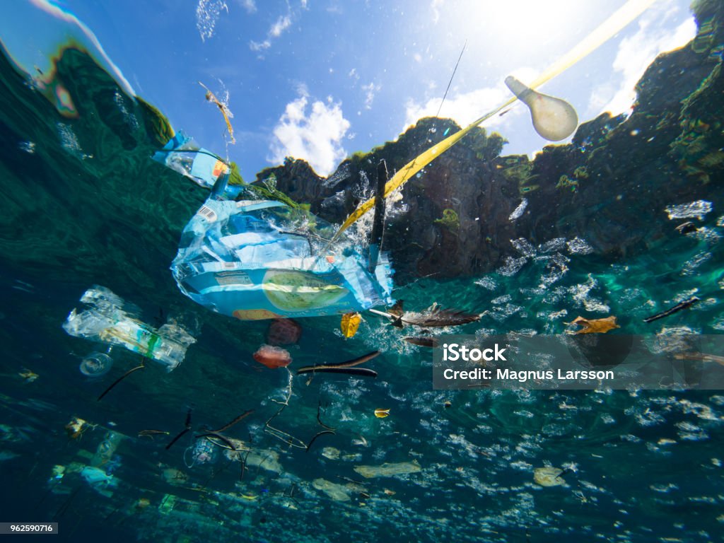 Plastic waste Plastic debris floating on the ocean surface, shot underwater. Sea Stock Photo