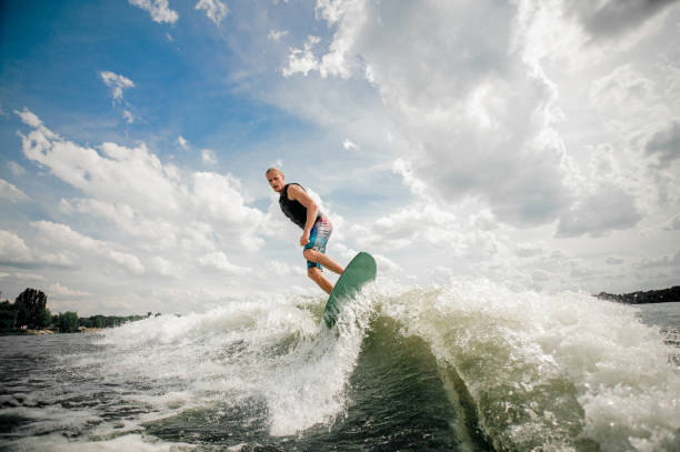 istock Tall man wakesurfing on the board down the river against the sky 962592270