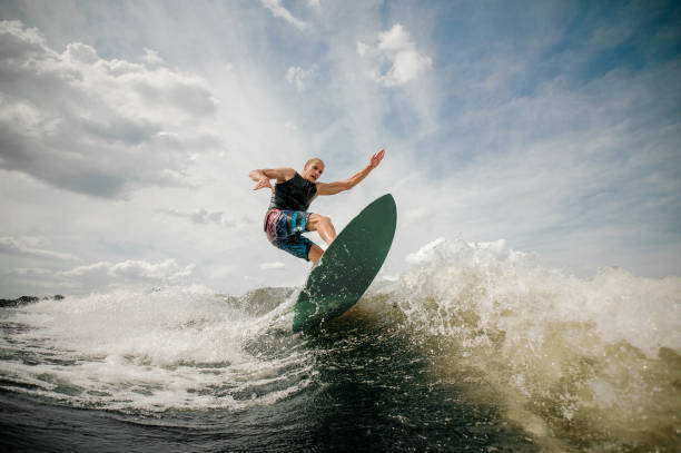 istock Athletic man wakesurfing on the board against the cloudy sky 962592320