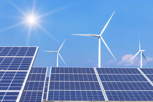 istock Rows array of  polycrystalline silicon solar panels and wind turbines generating electricity in hybrid power plant systems station 962592484