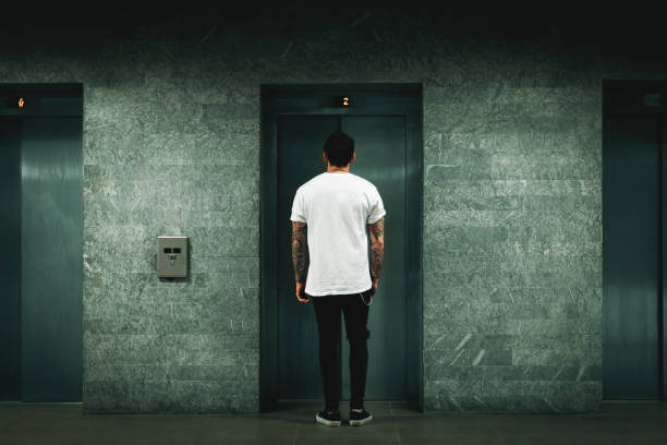 Man waiting for elevator Man waiting for elevator body adornment rear view young men men stock pictures, royalty-free photos & images