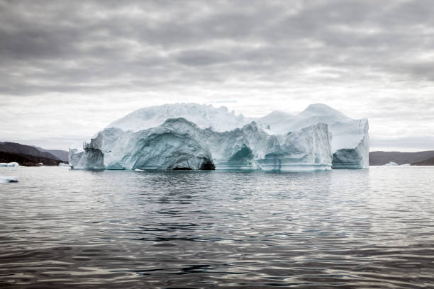 Iceberg floating off the coast of Greenland in the early morning on a calm sea