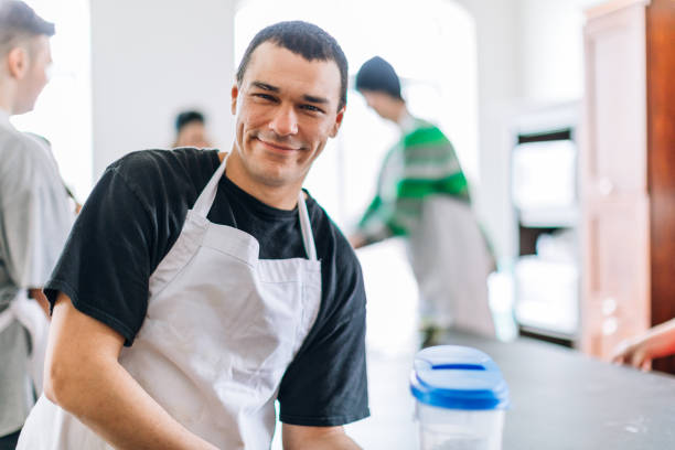 A young man looking at the camera in a community center. Cooking workshop