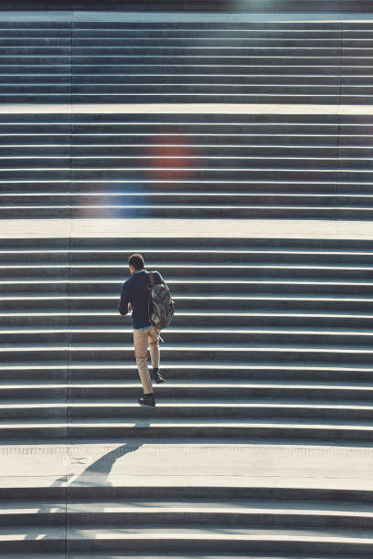 Rearview shot of a young businessman using a mobile phone while walking through the city