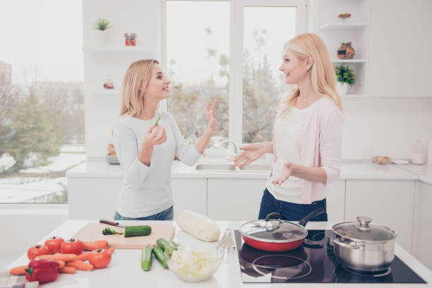 istock Cheerful positive housewives having conversation communication while preparing homemade meal dinner using stove frying pan vegetables discussing recipe, healthy lifestyle concept 962609782