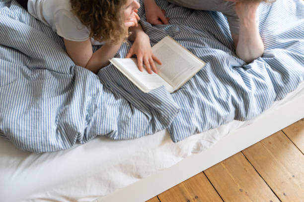 istock Young couple reading book in bed 962619010