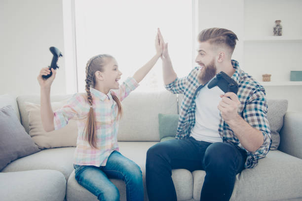 good job my best friend! cheerful cheerful family of positive stylish with single parent, father giving high five to daughter after victory in car racing game on x-box, sitting in modern house yelling yelling - xbox friends stock photos and pictures