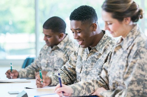 Group of military cadets take exam in military academy. They are writing in notebooks.