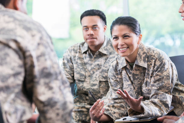 Female soldier talks during support group meeting Female soldier gestures while talking to fellow soldiers during a support group meeting. military uniform stock pictures, royalty-free photos & images