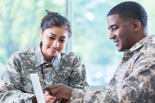 Hispanic female and African American male soldiers work on military academy assignment.