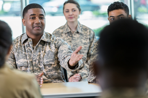 Curious mid adult African American soldier gestures as he asks a question while attending a seminar.