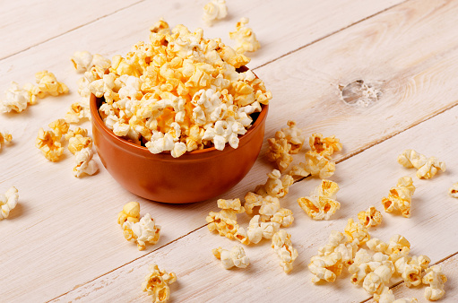 Cheese popcorn in a brown bowl on the wooden table