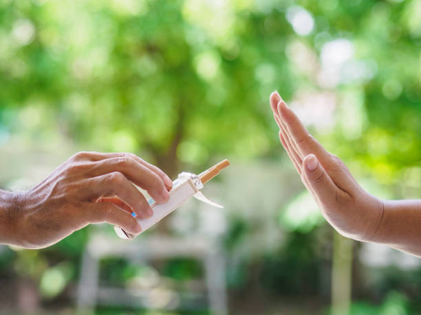 no smoking. close up of male hands holding cigarettes and proposing it to person. the human arm is gesturing with refusal on bokeh background. - quitting imagens e fotografias de stock