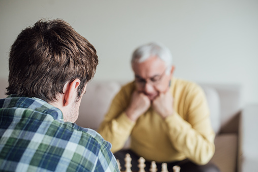 Old and young man playing chess together