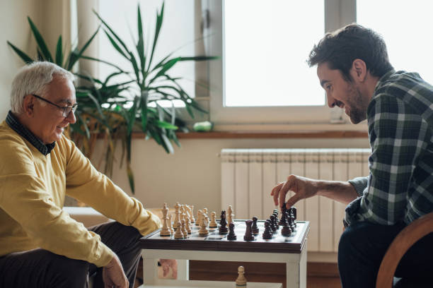 felices hombres jugando al ajedrez - juego de ajedrez fotografías e imágenes de stock