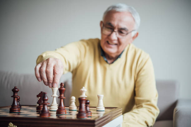 Elderly man making a move with chess piece Senior man holding chess queen senior chess stock pictures, royalty-free photos & images