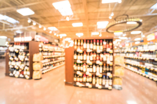 Blurred image of wine shelves with price tags on display at store in Humble, Texas, US. Defocused rows of Wine Liquor bottles on the supermarket shelf. Alcoholic beverage abstract background.