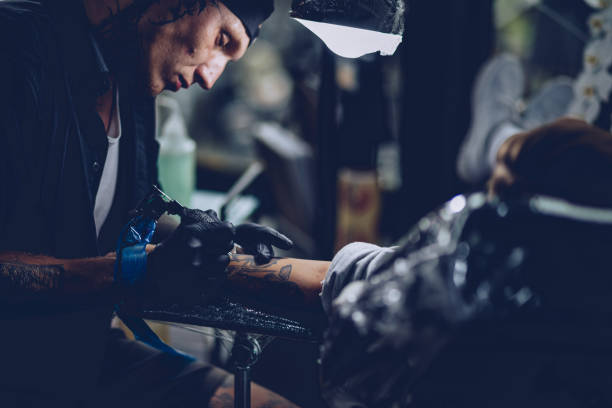 istock Artist making tattoo on customer's hand 962659238