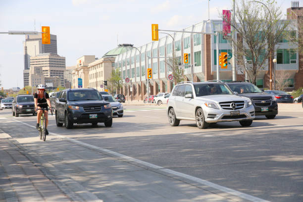 ciclista de joven junto con otros vehículos - canada main street manitoba winnipeg fotografías e imágenes de stock