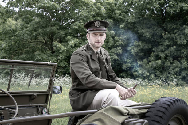 istock Handsome American WWII GI Army officer in uniform smoking cigar while sitting on Willy Jeep 962664524