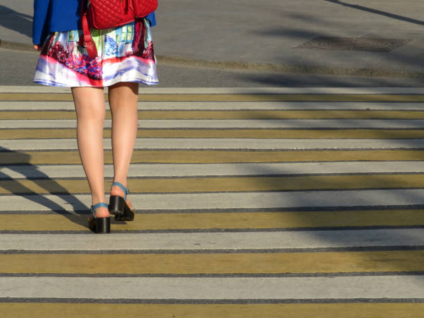 横断歩道で通りを渡る夏のドレスの女性 - single line yellow road asphalt ストックフォトと画像