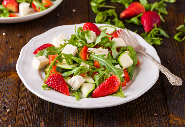 istock Fresh vegetable strawberry salad on white plate on natural rustic desk. 962672560